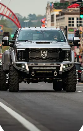 A white jeep parked on a large rock in an outdoor setting, showcasing its rugged tires and off-road capabilities.
